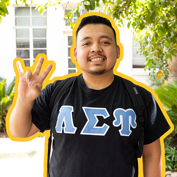 A male student wearing Alpha Sigma Psi shirt and showing the pitchfork with his fingers.