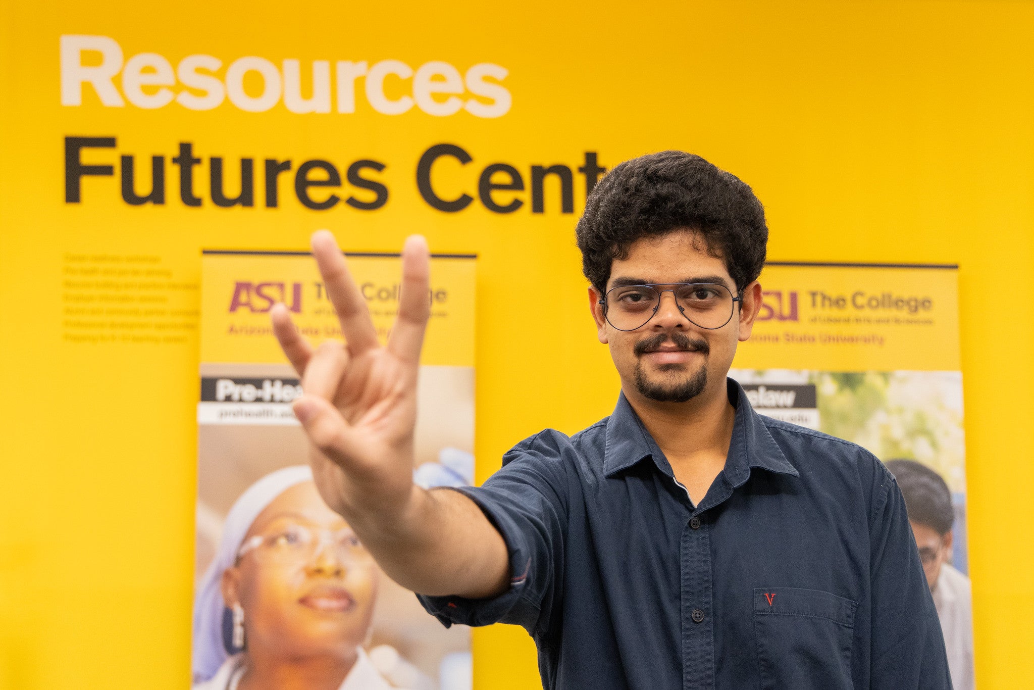 An ASU student holds forks up in front of the Futures Center.