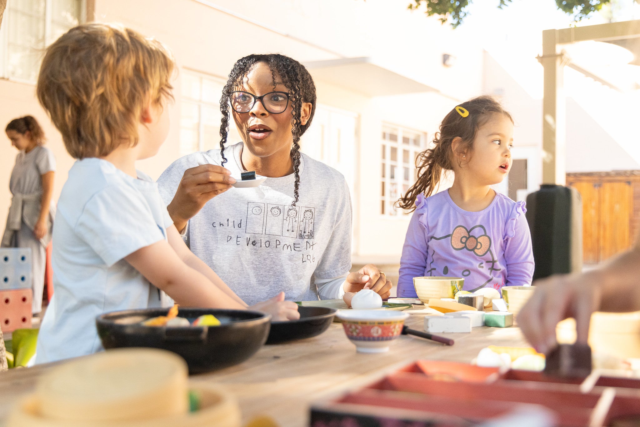 A student worker at the Child Development Lab engages in kitchen pretend play with preschool students.