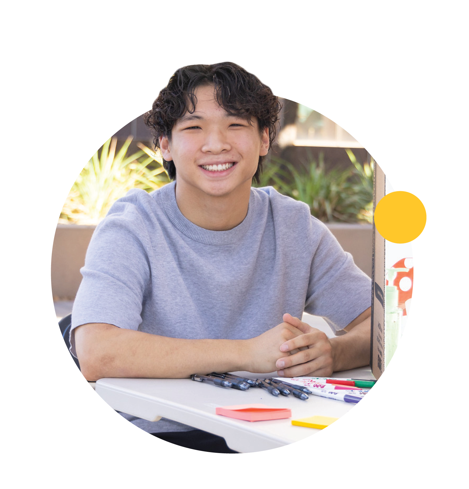 A student works at a table and smiles.