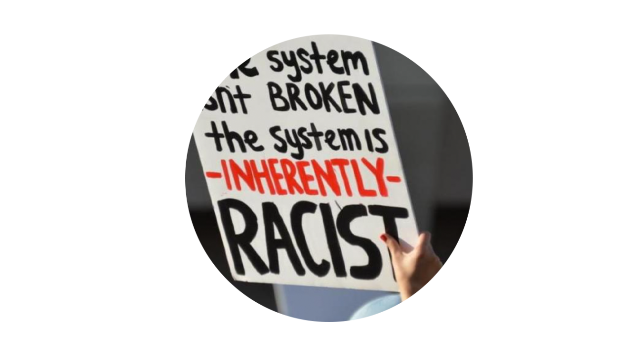 Protestor holding a sign that reads "The system is inherently racist."