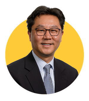 Portrait of Dean Kenro Kusumi in a suit in front of gold background