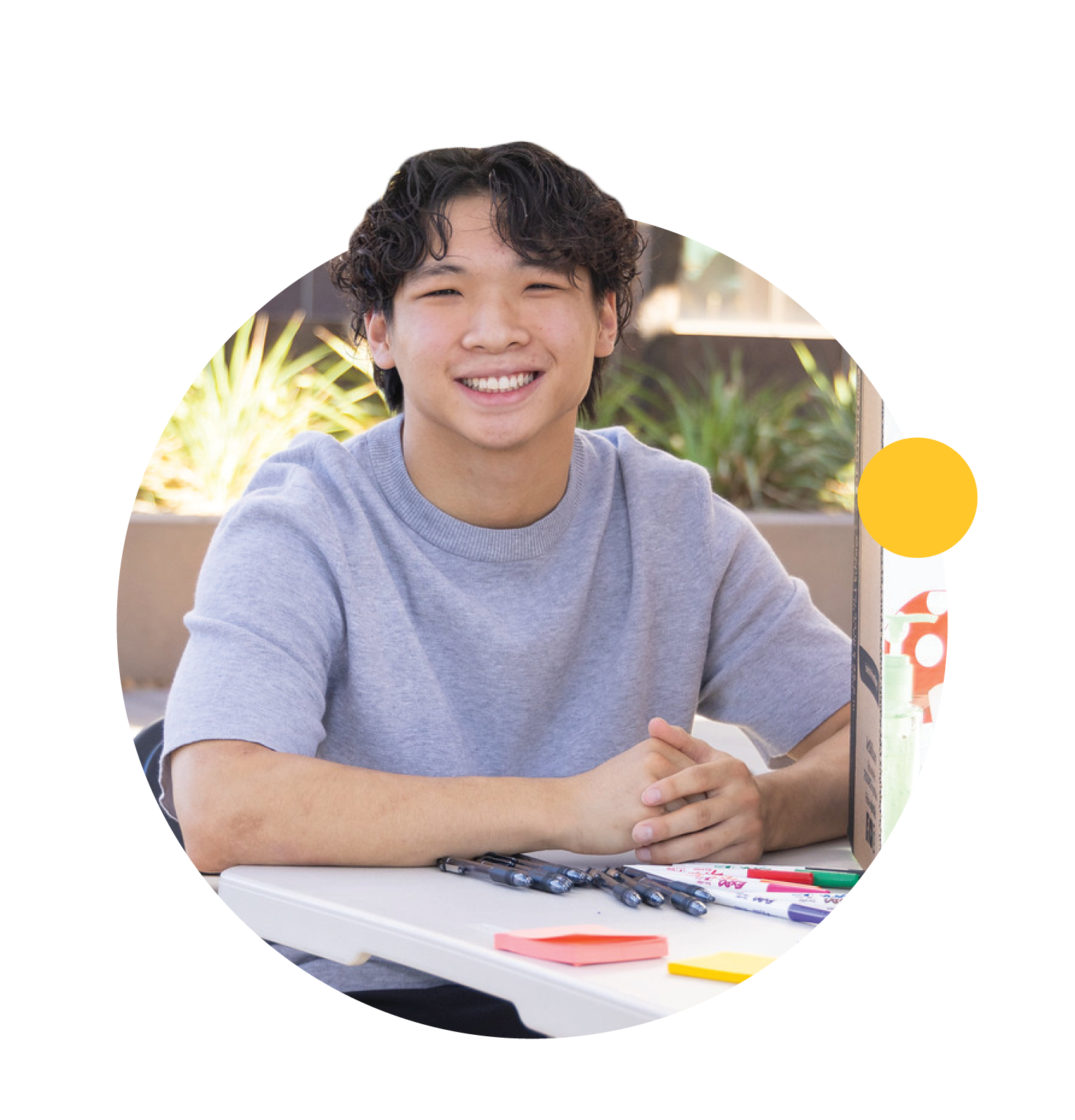 A student works at a table and smiles.